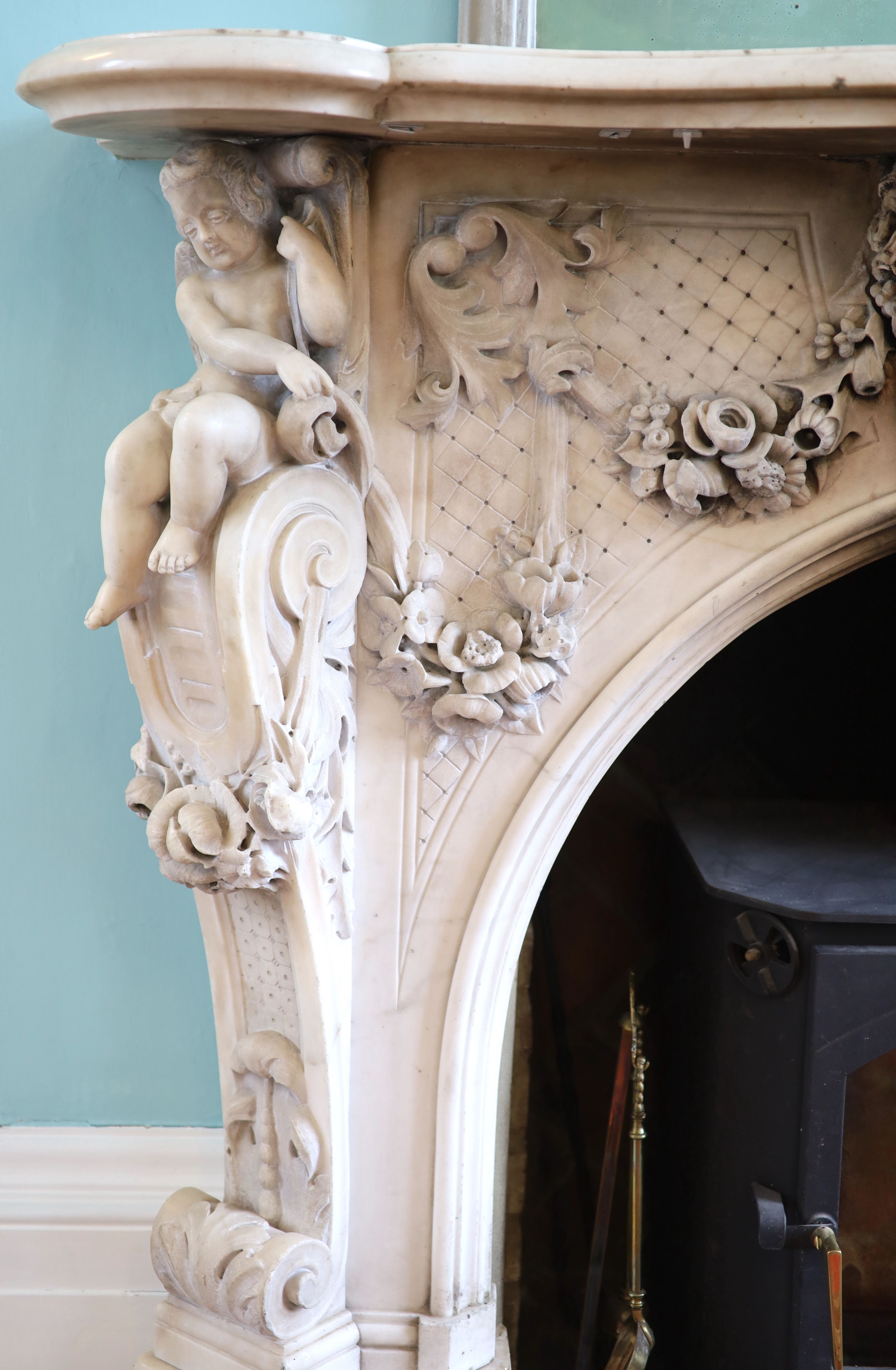 An important mid 19th century Italian white Carrara marble chimney piece, carved in the rococo taste, with seated putti, foliage swags